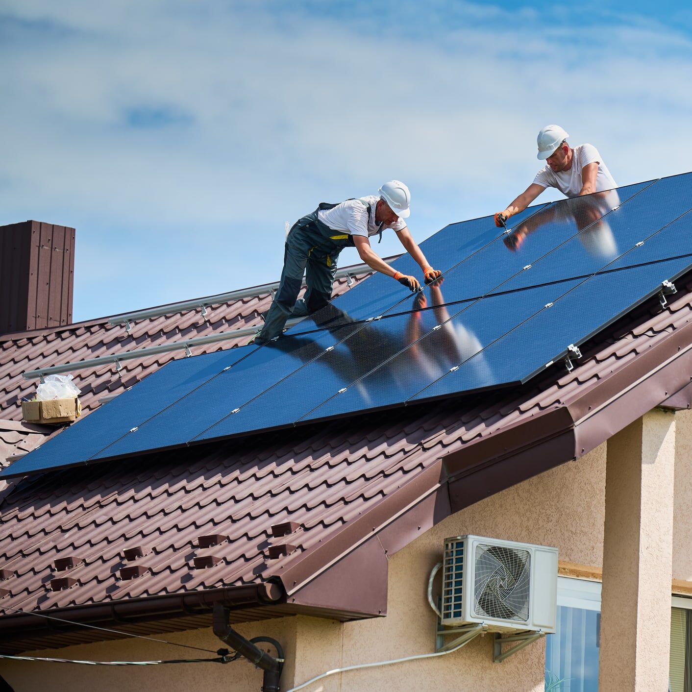 Worker building photovoltaic solar panel system on rooftop of house with help of hex key.