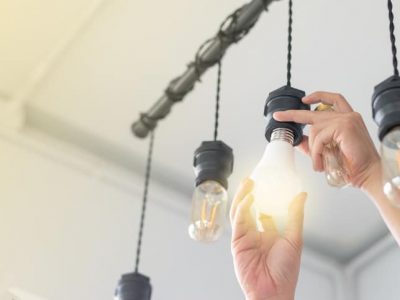 LED light Power saving concept. Asia man changing compact-fluorescent (CFL) bulbs with new bulb.