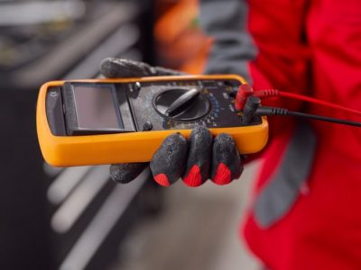 Male mechanic checking voltage of battery